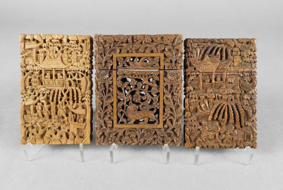 Carved Sandalwood Calling Card Cases, 19th C.: A grouping of three 19th century carved sandalwood calling card cases; 2 being of Chinese origin showing relief carved panels of figures and pavilions in treed landscapes, measuring 4.25" x 2.75"; tog