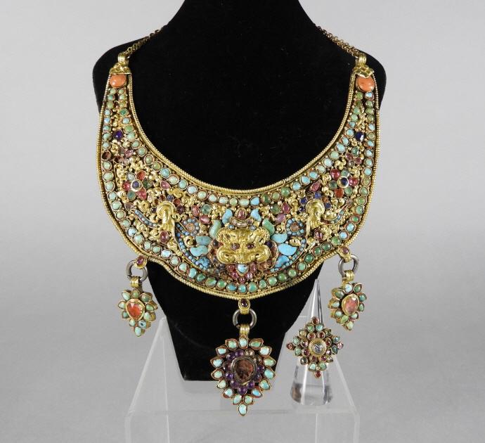 Rare Tibetan Gilt Repoussé & Hardstone Necklace: A rare Tibetan gilt repoussé and hardstone necklace, decorated with turquoise and coloured stones, centered by a gilt Tibetan snow lion, along with a matching ring. Late 19th Century. Condition, loss