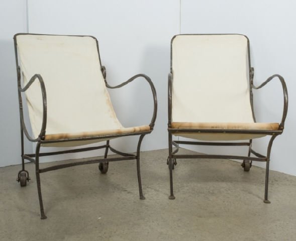 Vintage Wrought Iron Deck Chairs: A pair of vintage wrought iron deck chairs, each covered in a linen fabric, rear legs have iron wheels. 38 x 20 x 30 inches.