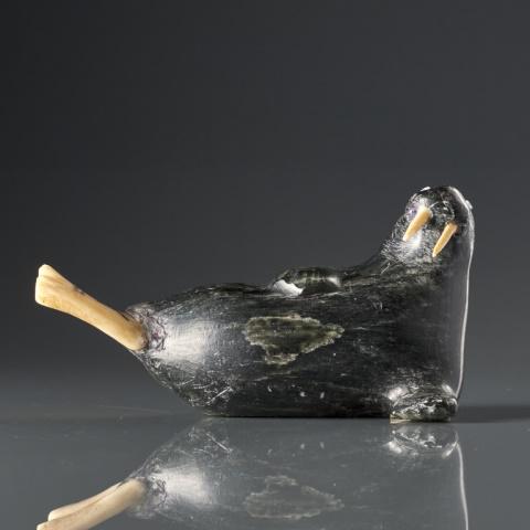 JOHNNY INUKPUK, R.C.A. (1911-2007): Johnny Inukpuk, R.C.A., Inukjuak (Port Harrison), black stone & natural material, walrus, the tail with an engraved narwhal spirit and bird, the eyes with bead insets, signed "Johnny" with artist's di
