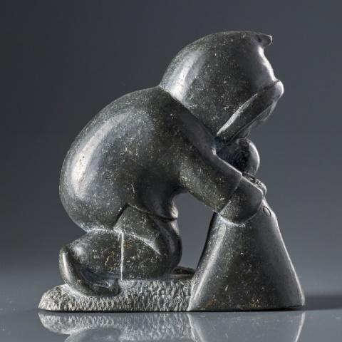 JOHNNY INUKPUK, R.C.A. (1911-2007) HUNTER: Johnny Inukpuk, R.C.A., Inukjuak (Port Harrison), black stone, hunter pulling a seal out of the water, signed with artist's disc number & syllabics (ja-ni). Measuring, 5” x 5” x 2”.