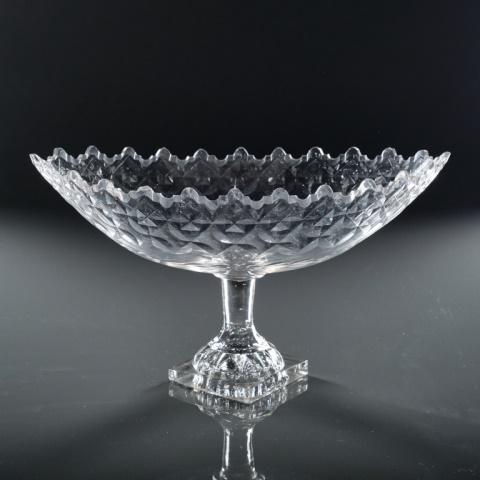 GEORGE III ANGLO IRISH CUT GLASS CENTERPIECE: England, circa 1790, the navette shaped body with diamond shaped panels over a laurel leaf cut band, rising to a van dyke castellated rim, raised upon a short cylindrical stem atop a cupped 'lemon squ
