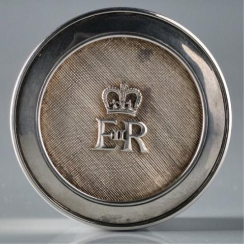 20TH C. STERLING SILVER PILLBOX BY GERALD BENNEY: The circular case fitted with a conforming lid decorated with the British Royal Cypher for Her Majesty Queen Elizabeth II against a cross - hatched field, the underside bearing impressed London hallma
