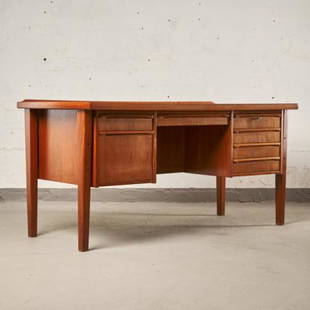 MCM TEAK KNEEHOLE DESK BY SVEN MADSEN: Denmark circa 1960, the graceful concave shaped top over a compliment of fitted drawers, the front fitted with open book shelves, raised overall upon tapering squared supports, minor blemish to the