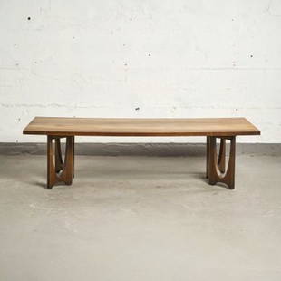 MCM 'BRASILIA' WALNUT COFFEE TABLE BY BROYHILL: USA circa 1960, the figured rectangular walnut top raised on shaped bracket supports, measuring 16" high x 60" long x 22" wide.