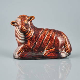 ROCKINGHAM GLAZED EARTHENWARE LAMB: Yorkshire England circa 1850, the hollow body moulded figure of a recumbent lamb decorated with a mottled high glaze, the reverse bearing remnants of a BADA (British Antique Dealers Association) label