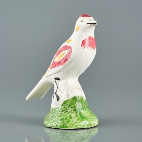 STAFFORDSHIRE PEARLWARE SONG BIRD: England circa 1820, the figure of a song bird decorated with magenta & ochre painted detail, perched atop a green mossy base, measuring 3.5" high.