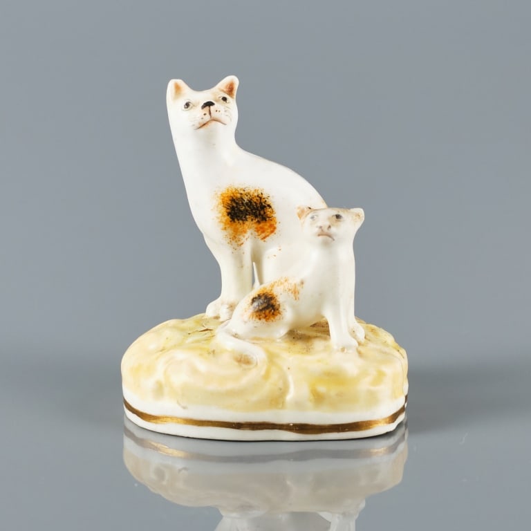 STAFFORDSHIRE PORCELAIN CAT & KITTEN: England circa 1830, likely Alcock Potteries, showing a cat and kitten with tan and black sponge painted detail, both seated upon a ripple molded yellow base, area of distress to glaze to top base, mea