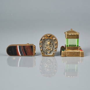 THREE VICTORIAN MATCH SAFES: One match safe with a green glass receptacle, having a lid, fitted to an engraved brass base, and adorned with coloured stones. Two vesta match safes, one Victorian agate example and another in the sh