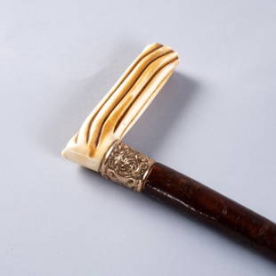 GENTLEMANS WALKING STICK: A hickory walking stick mounted with a natural material handle and decorated chased 10kt yellow gold (unmarked and tested) band, measuring 34.75 inches.