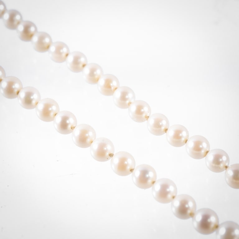 CULTURED PEARL NECKLACE: A string of cultured pearls, each approximately 5.7mm, total length 24 inches, clasp stamped 10K.