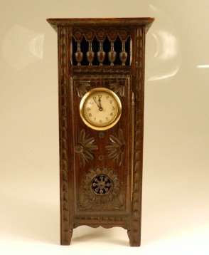 Late Arts and Crafts Desk Clock: Late Arts & Crafts desk clock encased in carved wood box, unmarked, floral pattern, 14 inches tall x 3.5 inches wide