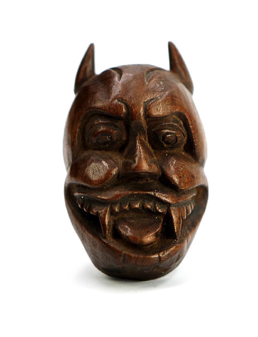 JAPANESE NETSUKE CARVED MASK; EDO PERIOD (1603-1867): A character trope in Noh theatre, this netsuke depicts a "Hannya" mask-typically representing a scorned woman turned into a demon. H 1 3/4 in ( 4.4 cm) W : 1 in (2.5 cm )