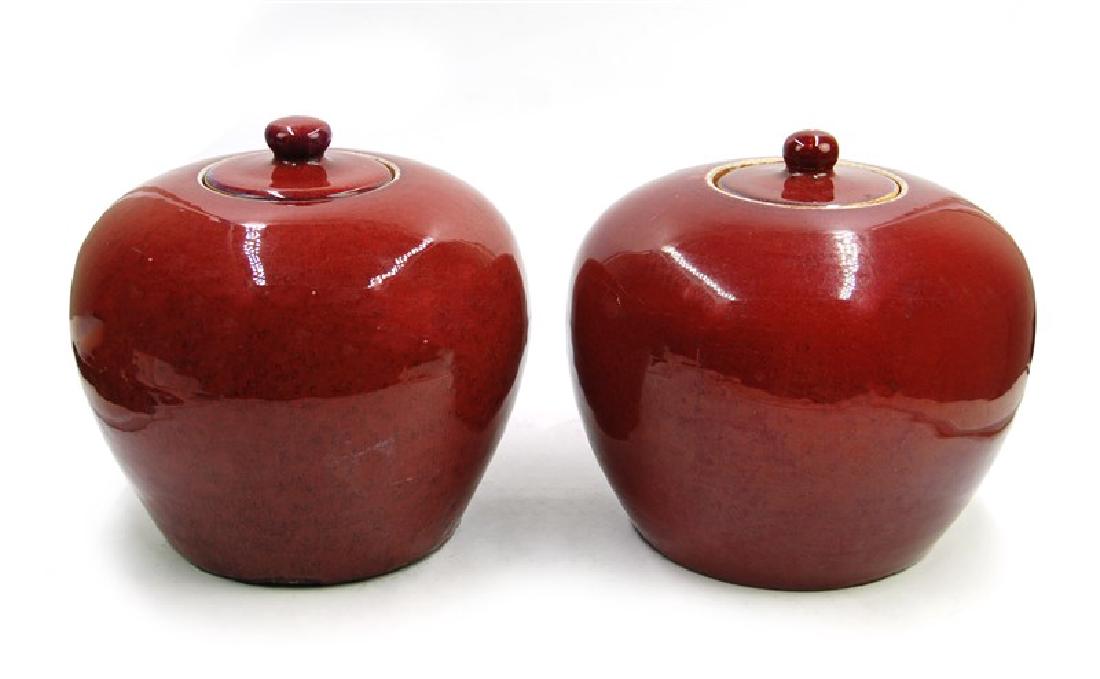 PAIR RED LIDDED JARS: A pair of red glazed jars made in apple shape, with lids at top. H:8in (20.3 cm) W:8 1/2in (21.5 cm)