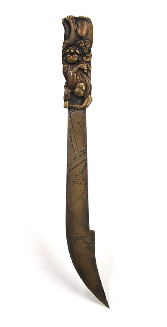 JAPANESE BRONZE KNIFE; EDO PERIOD (1603-1867): The handle of the knife is a man carving a foo dog, and the body of the knife is carved as the man's garden. L:12 1/2in (31.7 cm) BLADE: 8 1/2in (21.59cm)