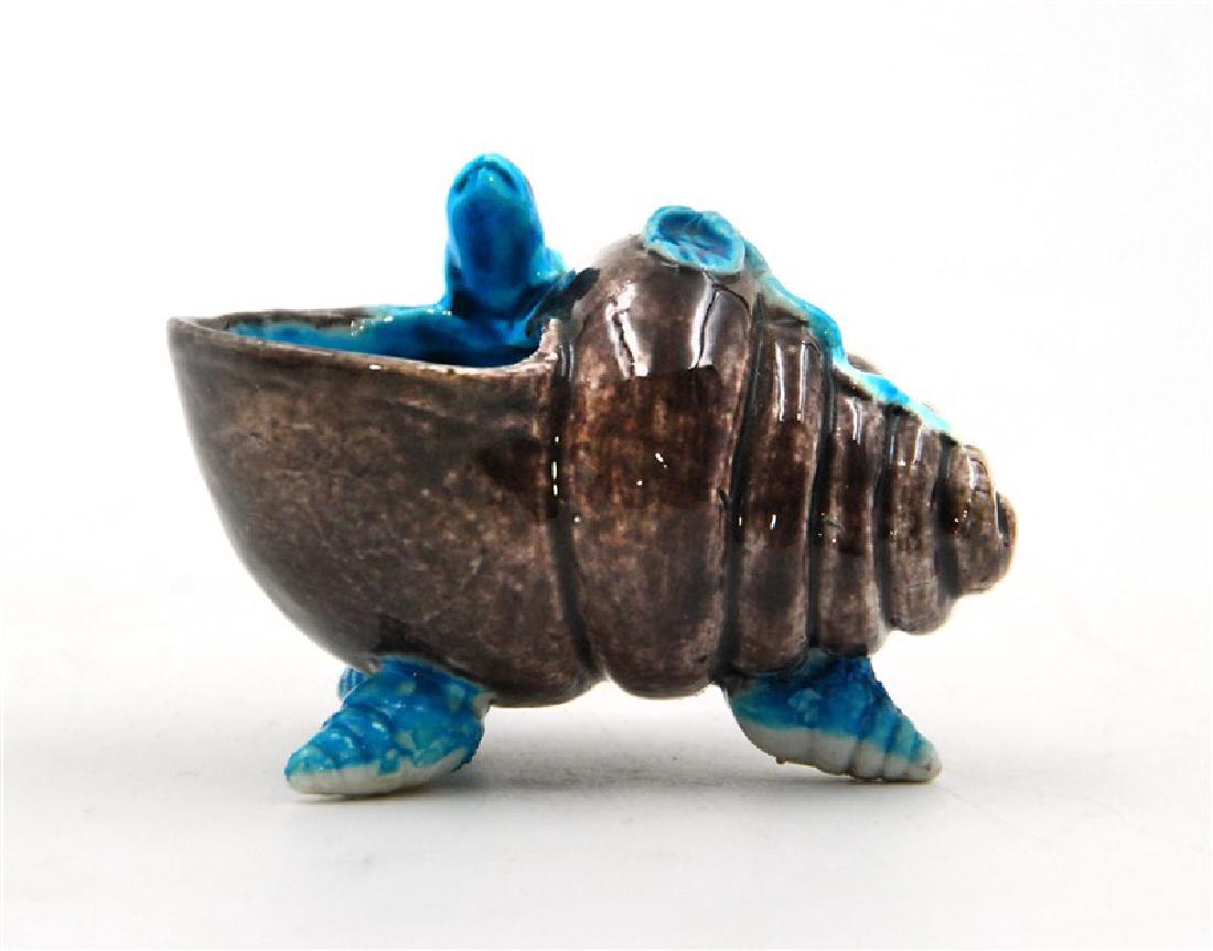 PORCELAIN SHELL BRUSH DIPPER: A small brush dipper glazed in duo-chrome of charcoal brown and a bright turquoise blue - with frog on top and sitting on three small shell form feet. H:3in(7.6cm) W:2 1/4in(5.7cm)