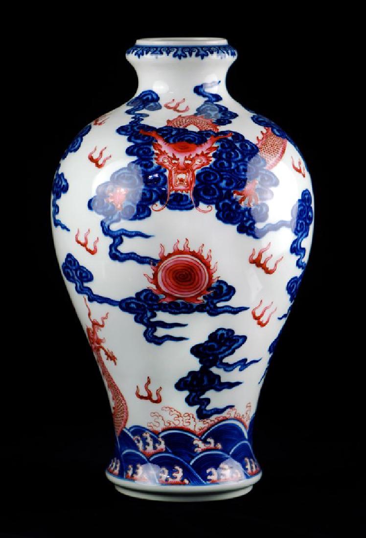 WHITE GROUND DRAGON VASE: With a small neck and mouth, this vase has been decorated with red dragons among blue clouds. A Qianlong style mark is on the bottom. H:13in(33cm) W:7 1/4in(18.4cm) M:2in(5.1cm)