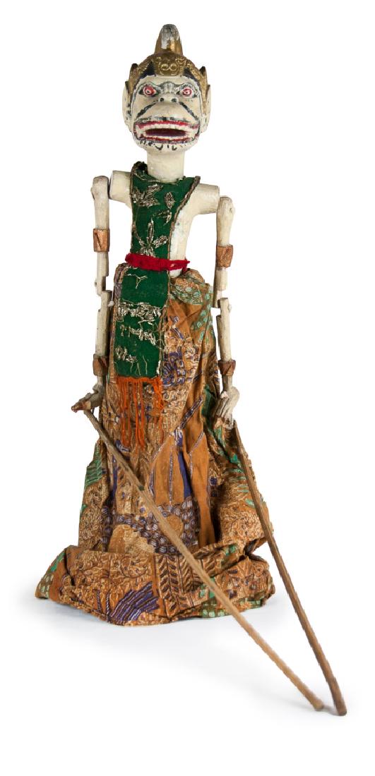 WOOD CARVED AND PAINTED WAYANG PUPPET: This wood carved Wayang puppet is painted in red on eyes and mouth and gold on the headdress, decorated with silver leaf patterns on the green vest, and wearing an orange dress. H:23 1/2in(59.7cm)