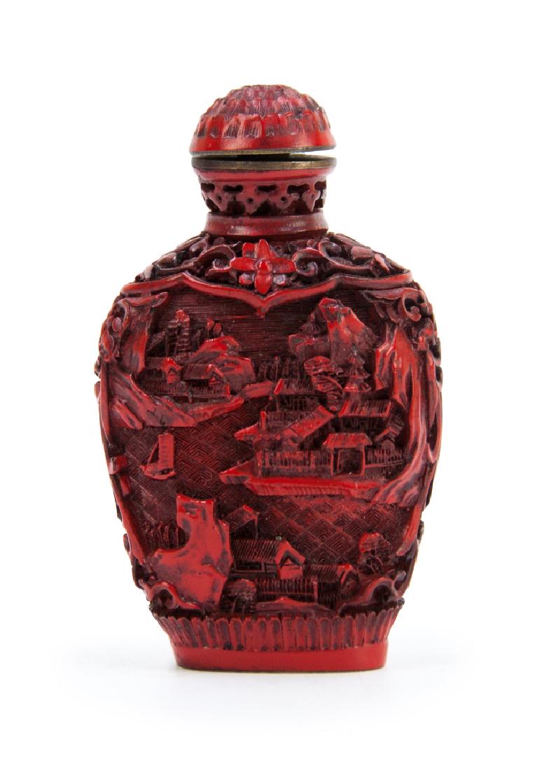 CINNABAR LACQUER CARVED SNUFF BOTTLE: With a topper carved into a flower bud, the body of this cinnabar lacquer has been carved on both faces with a scene oh housing among the mountains, framed within floral scrollwork. H:3in(7.6cm)