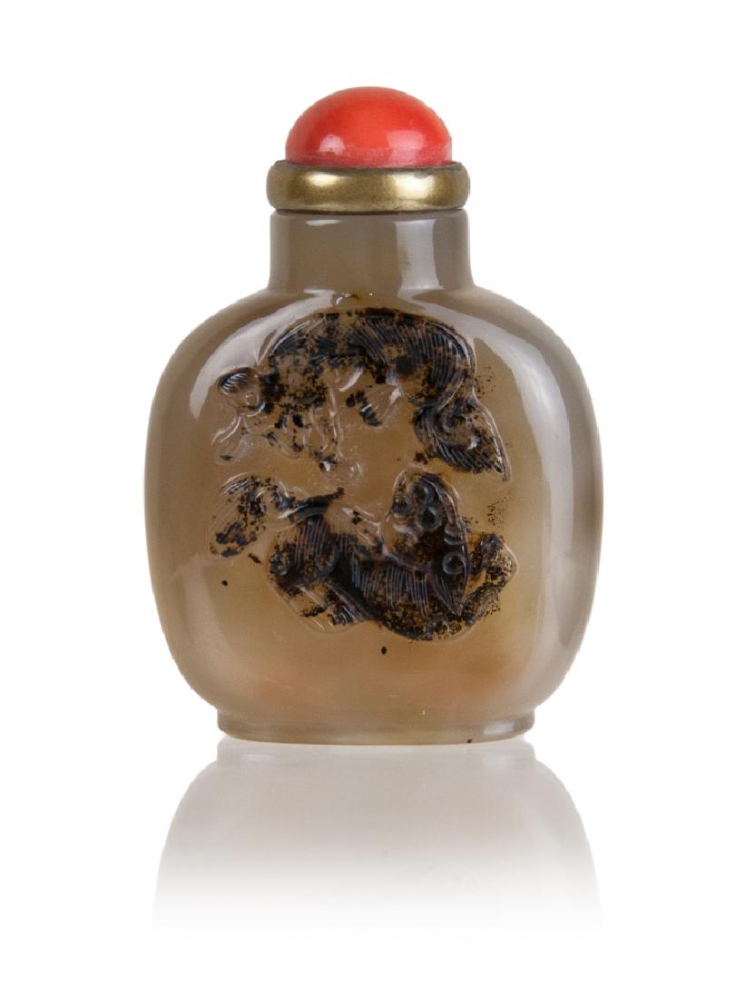 AGATE SNUFF BOTTLE, TWIN FOO DOGS: An agate snuff bottle with spotted black inclusions that the artist took advantage of to carve into a pair of foo dogs and it topped with a red stopper. H:2 3/4in(7cm) 95g
