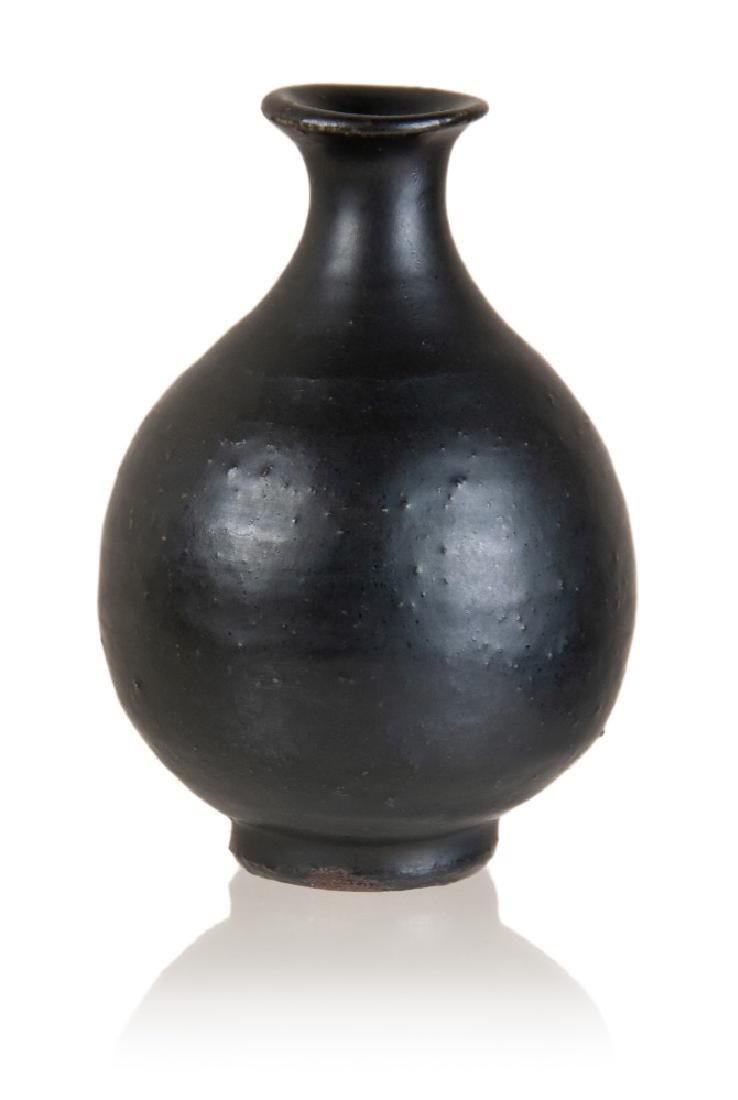 SMALL BLACK EARTHENWARE KOREAN VESSEL: A small Korean black earthenware vessel featured with a flaring mouth, a short neck and a globular body. H:5in(12.7cm) W:3 1/2in(8.9cm) M:1in(2.5cm)