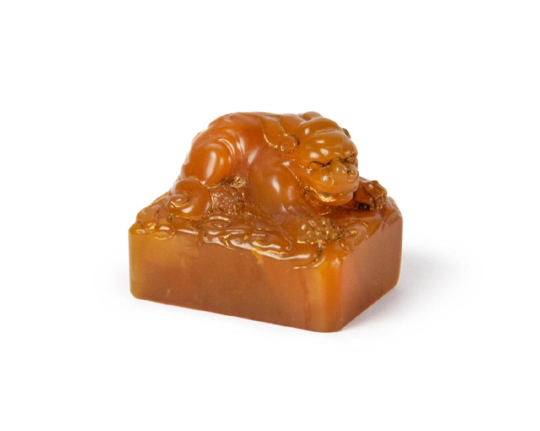 YELLOW SOAPSTONE SEALS AND CARVINGS, BEAST: A cube supporting a seated, two-horned lion-like beast, , the stone depicting isolated patches glow to the otherwise creamy honey matrix 30g 1in(2.5cm) 1 1/4in(3.2cm)