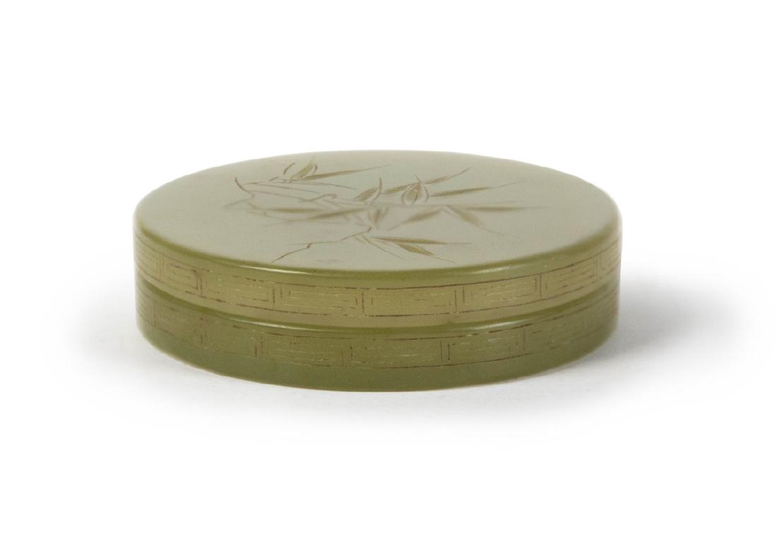 CARVED JADE PASTE BOX: A flat circular jade paste box, the sides decorated with geometric leiwan bands and the top lid incised with bamboo. 57g D:2 1/4in(5.7cm) H:5/8in(1.9cm)