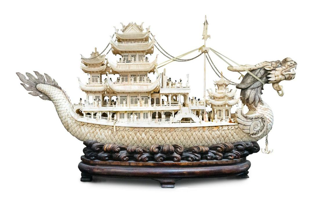 LARGE MONUMENTAL BONE CARVED DRAGON BOAT: The vessel constructed from veneers of animal bone, the hull with overlapping fish-scales, the splitlevel deck set with a central pagoda joined by arched bridges to flanking pagodas, variousfigures ma