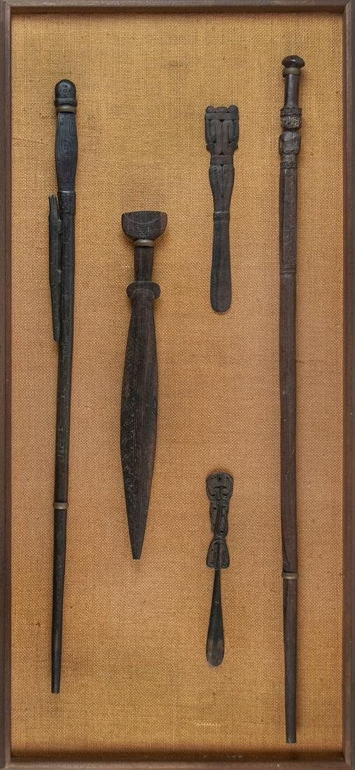 A COLLECTION OF FIVE POST MEDIEVAL WOOD IMPLEMENS: A collection of five wooden implements in medieval style, framed and hung for display. There are two walking sticks, one knife, and two ceremonial instruments. The backing is caned, and the plywood di
