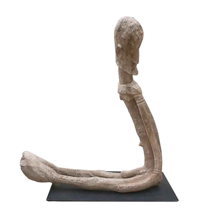SCULPTURE WOOD FIGURE, MALE , PAPUA NEW GUINEA: Sculpture in carved hardwood fabrication. Country of origin: Papua New Guinea. Depicts a figure with a hoof attached to its feet. Male, and mounted to an ebony tone metal base H:25.5in(64.7cm) W:26in(