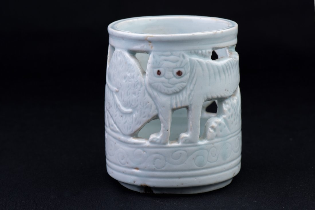 PORCELAIN BRUSH POT: Of cylindrical shape; made of porcelain; hollowed out with a “wild cat in the woods” design; supposedly made in Korea; H: 4 3/4’’