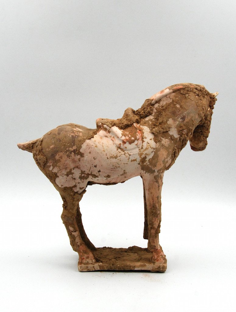 HAN DYNASTY WHITE CLAY HORSE: Dating back to the Han Dynasty, this white clay horse is unglazed and hollowed out. The horse is outfitted with a saddle, with a groomed mane and tail and stands erect, with its head turned back.