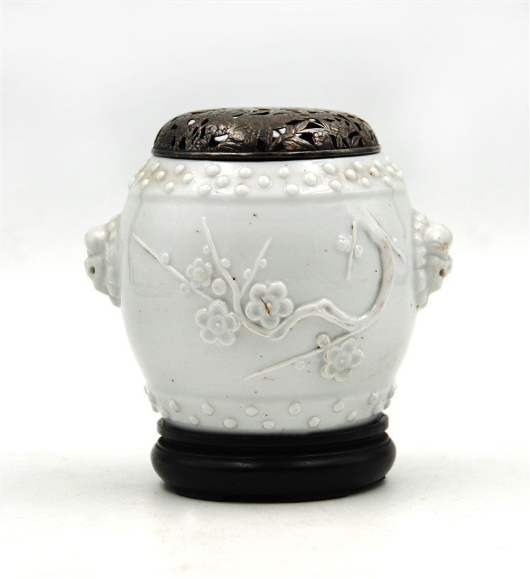 LIDDED BLANC DE CHINE PORCELAIN INCENSE HOLDER: Barrel shaped and decorated with protruding masks on both sides and a cherry blossom branch, this blanc de chine incense holder is lidded with a open work floral lid. H:4.5 W:3.5