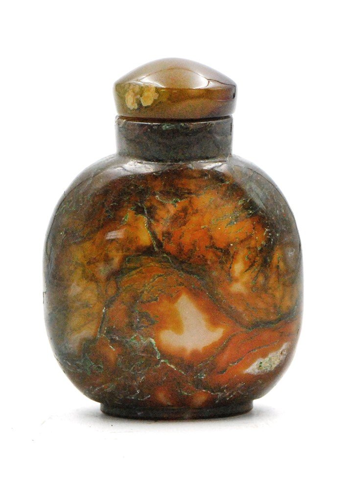 AGATE SNUFF BOTTLE: The well-hollowed bottle is of rounded form on an oval foot rim. The reddish-brown stone is suffused with moss-like, greenish-blue and white inclusions and topped with creamy brown agate stopper. H: 3