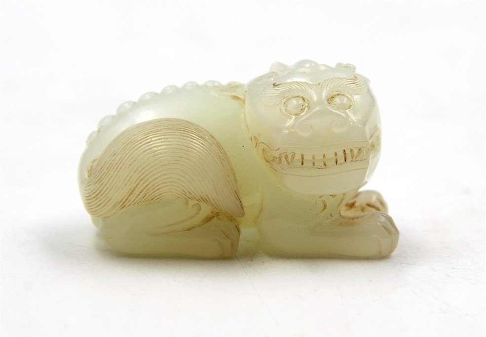RECUMBENT FOO DOG JADE CARVING: Carved from a pale white jade, with bared teeth and bushy tail. L:2 51g