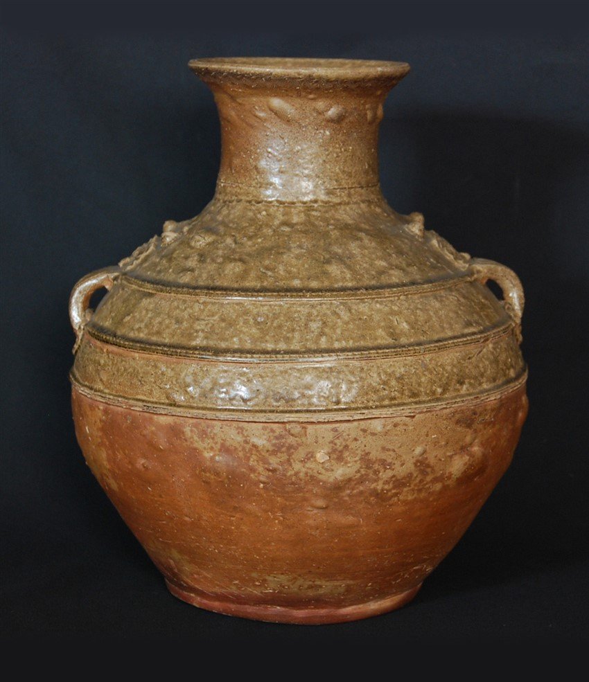 HAN DYNASTY CERAMIC JUG: With a flared mouth, this ceramic jug from the Han Dynasty has a very organic surface texture with three circumferential rings and flanked by two small handles. H:15 W:12 1/2