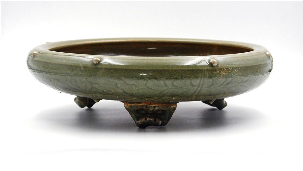 CELADON GLAZED TRIPOD INCENSE BURNER: Supported by three squat legs, with an everted mouth and decorative nodes along the top rim and bottom, the body of this incense burner has incised floral patterns which are accented from the pooling 