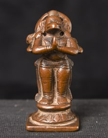 Miniature in size, but resolute in stance, this 17thC solid cast bronze Hanuman stands with an open
