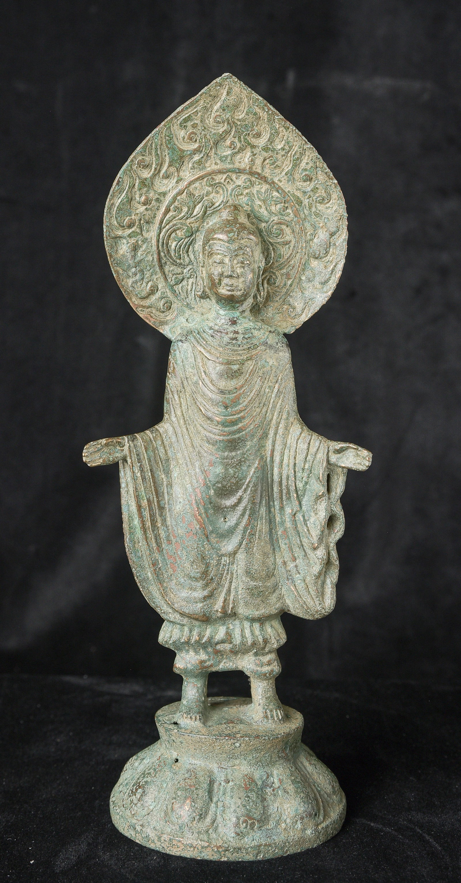 Early style standing Chinese bronze Buddha.: Early style standing Chinese bronze Buddha. The high level of detail in the robes and halo appear to be created by carving out the detail rather than casting it into the metal. This is a very