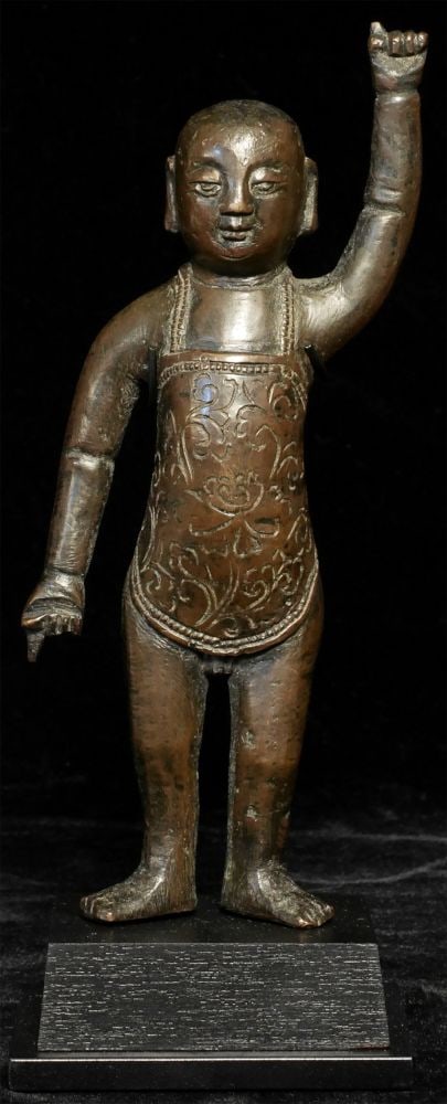 A 16th/17thC solid cast Chinese Ming Bronze Baby: A 16th/17thC solid cast Chinese Ming Bronze Baby Buddha. He is dressed in a short tunic and is pointing to heaven and earth as a witness to his birth. There is a shortening to one index finger, but