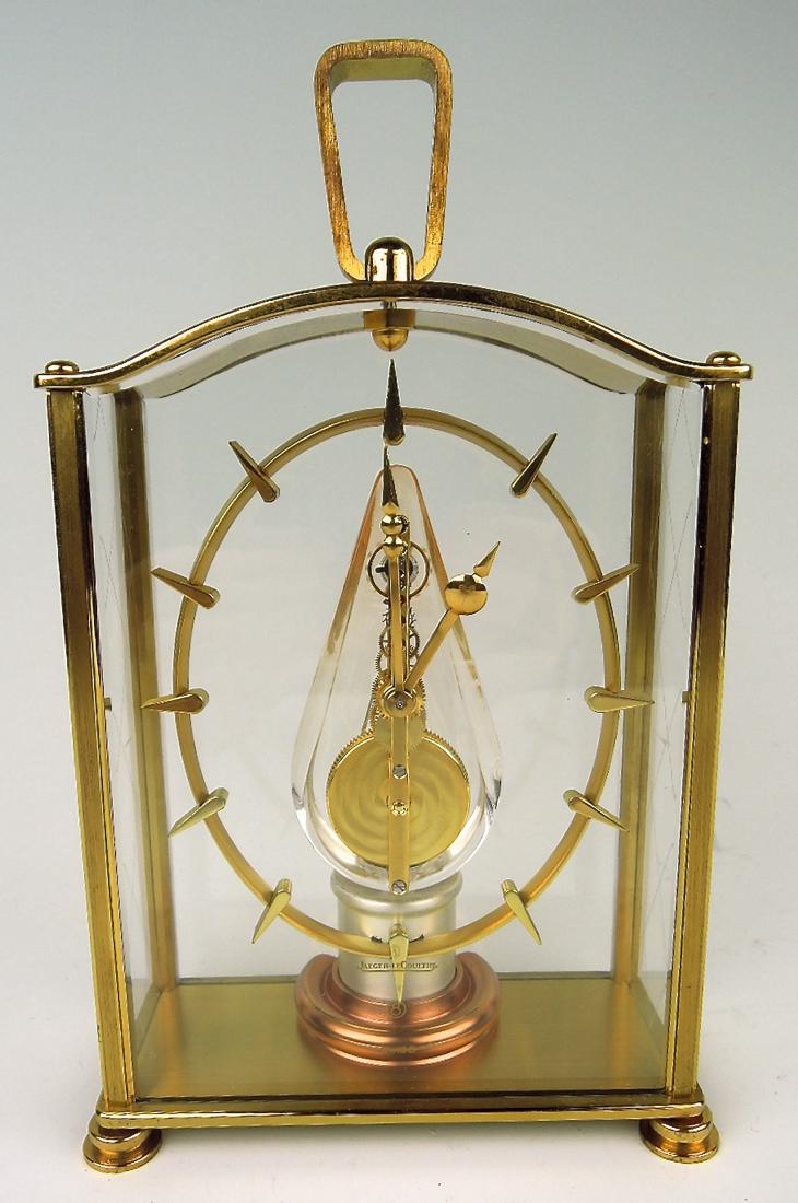 Rare Jaeger LeCoultre Skeleton Clock: Mid 20th C, with modernist stylized hour markers mounted on central oval surrounding a clear teardrop in center with gilt brass inline movement, 8 day skeleton clock, No333, in a gilt brass case with