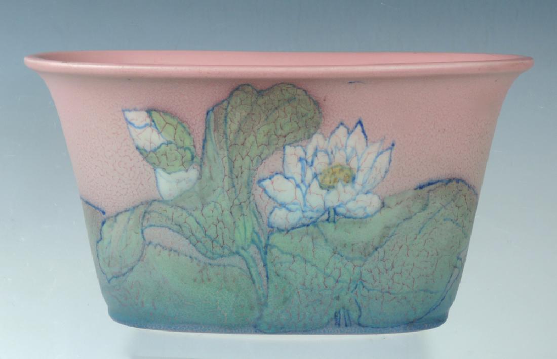Rookwood Earthenware Lotus Jardiniere: Matte glazed with lotus blossoms on both sides and pink ground, decorated by Sally Coyne, 1930, impressed factory mark and artist's cipher, 6" x 10.75", very good condition
