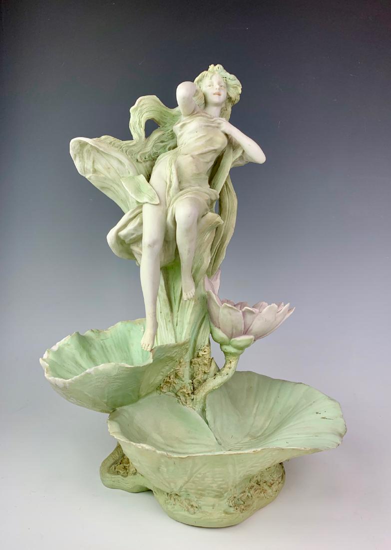 Royal Dux Art Nouveau "Maiden & Lily Pads": Circa 1900, made of porcelain, figural maiden perched atop lily pads and flower, done in green tones, signed with pink triangle, chipping around edges of lily pads, interior crack on very bottom, 15" 