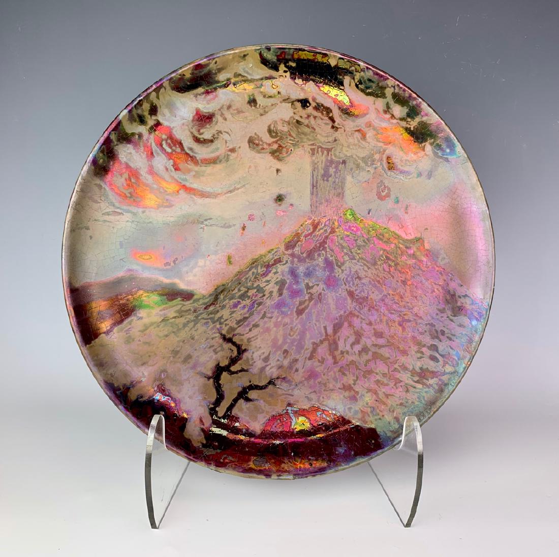 Clement Massier "Volcano" Charger C. 1900: Decorated with an erupting volcano, phoychrome iridescent enamels, signed on back "Clement Massier Gold Juan A.M." and stamped, good condition, back rim edge has minor roughage in glaze, 13" diameter