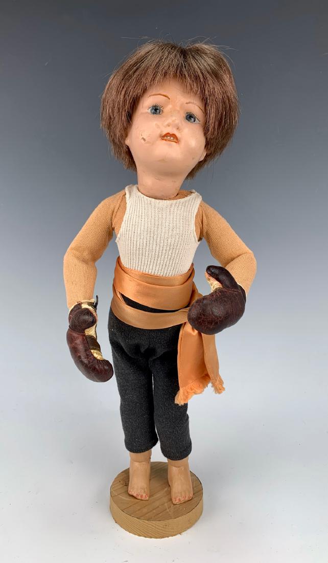 American Schoenhut "Boxer" C. 1920: Painted blue eyes, face repainted, synthetic wig, on wooden stand with metal post, dressed as boxer with vintage boxing gloves, fair condition, 15"