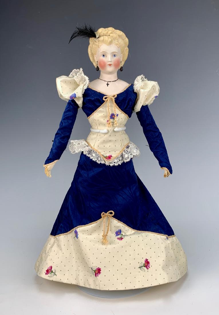 German Parian C. 1870: Blue painted eyes, fancy blond hairdo, pierced ears, molded beads in hair, molded beaded necklace with cross, repair on left neck line, antique cloth body with leather arms and separately stitched fin