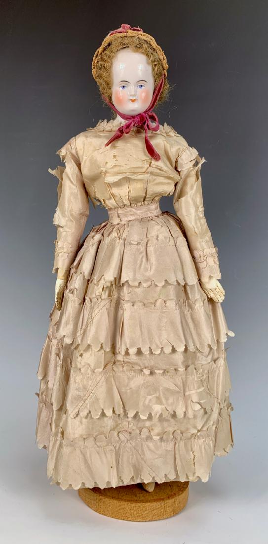 German Biedermeier China Doll C. 1850: Painted blue eyes, bald head with painted black circle under mohair wig, slightly smiling mouth, muslin body with leather hands (appears original), original antique dress of frail silk and multi-layer