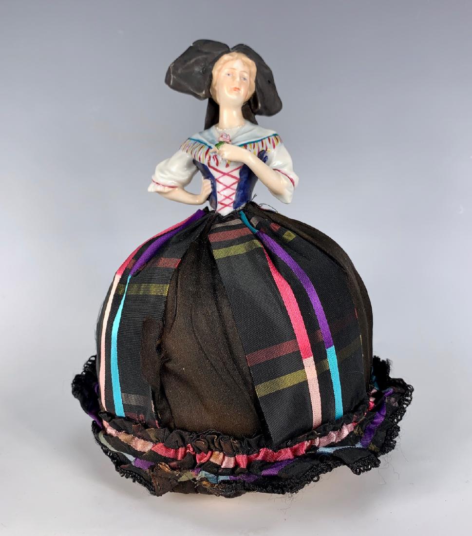 German Porcelain China Pin Cushion Doll C. 1920's: Molded Alsace costume with chip on head bow, over stuffed base (stain on base), satin plaid skirt, good condition, 8.75"