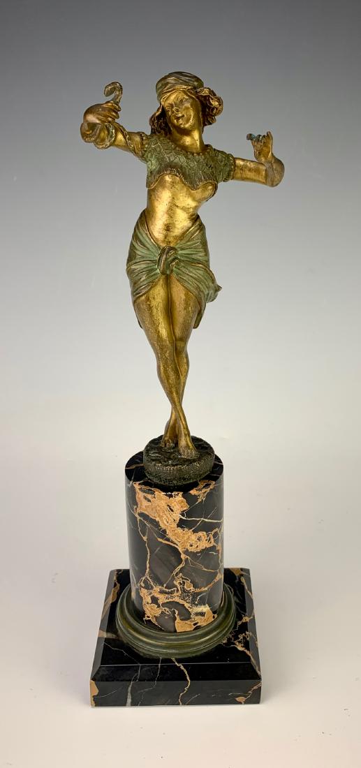 Georges Flamand (1895-1925) "The Snake Charmer": Circa 1910, gilt bronze of a female snake charmer in scantily clad top and bottom, mounted on a black veined marble cylindrical base, signed in bronze "Flamand", good condition, normal wear commensura