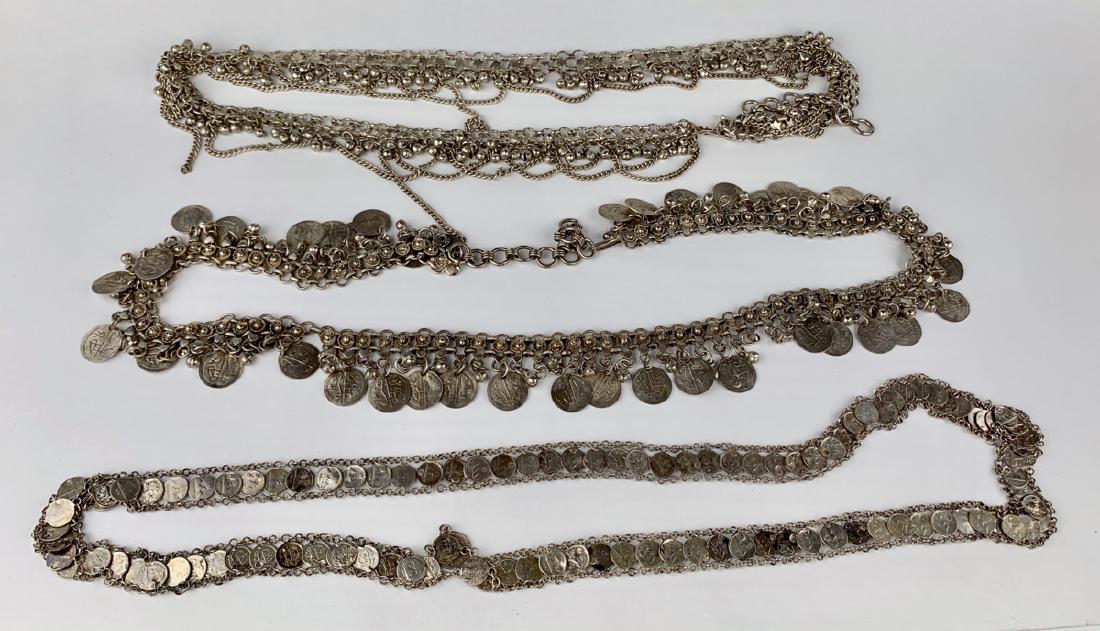 3 Persian Metal Coin Ladies Belts: 2 belts are made up of silvered chains with suspended coins and the other has no coins but stars and chains, all three are made of metal, good condition, 40" waist largest